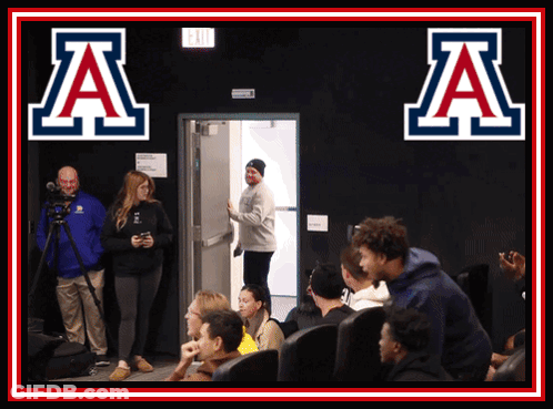 Group Sitting In Front Of Sign Saying A GIF