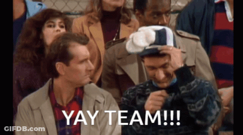 Group Sitting In Stadium With Yay Team Hat GIF