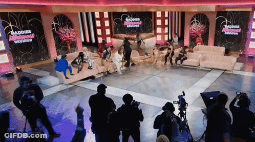 Group Sitting On Couch In Front Of Baddies Reunion Sign GIF