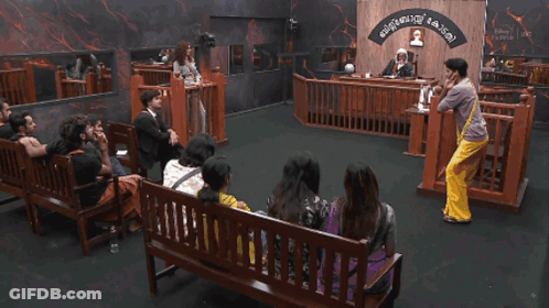 Group Sitting On Courtroom Benches With Malayalam Sign GIF