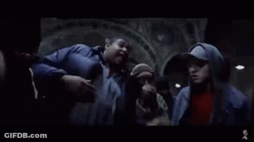 Group Standing Around Man In Dark Room GIF