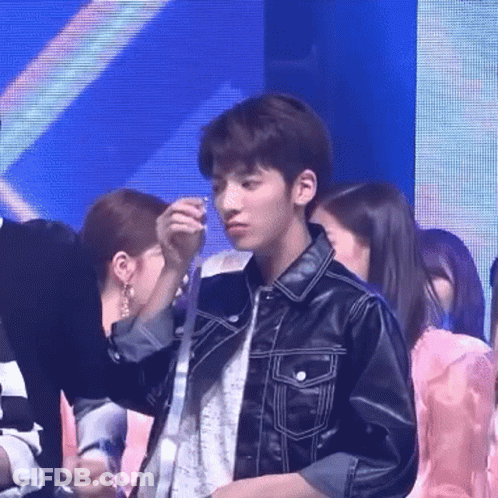 Group Standing Around Man In Leather Jacket Holding Necklace GIF