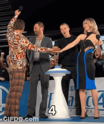 Group Standing Around Table With Number 4 GIF