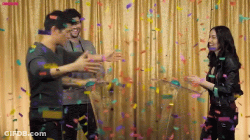 Group Standing Before Curtain With Confetti GIF