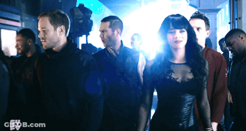 Group Standing In Dark Room With Syfy Logo GIF