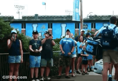 Group Standing In Front Of Blue Building With Letter I GIF