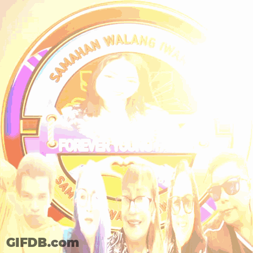 Group Standing In Front Of Forever Young Sign GIF