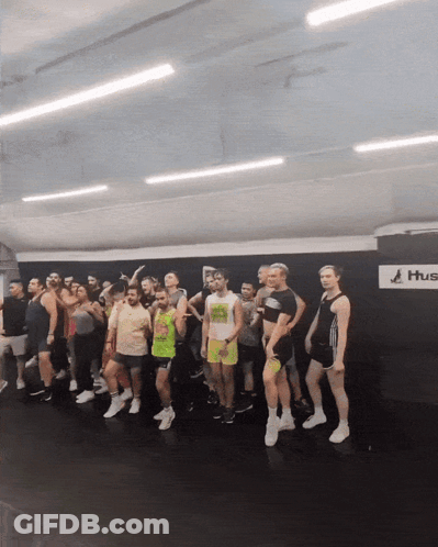 Group Standing In Front Of Wall Saying Hus GIF