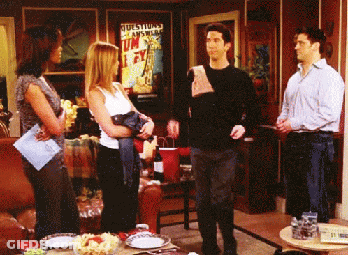 Group Standing In Living Room With Questions Answered Sign GIF