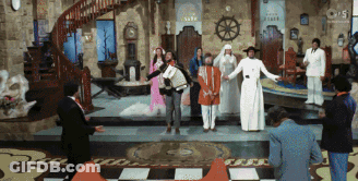 Group Standing In Room With Clock Saying Clock GIF