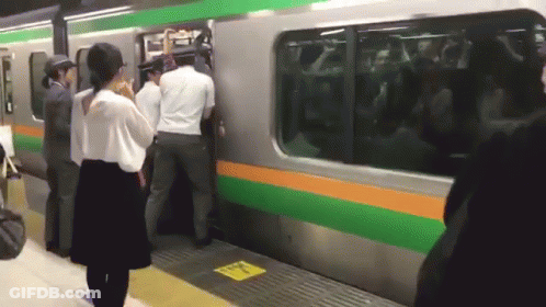 Group Trying To Board Train With Yellow Sign Saying A GIF