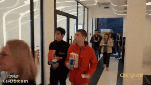 Group Walking Down Hallway With Cine Grand Sign GIF