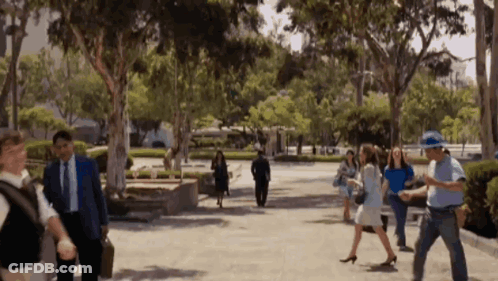 Group Walking Down Sidewalk Surrounded By Trees GIF