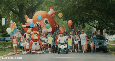 Group Walking Down Street With Balloons And Bull Mascot GIF