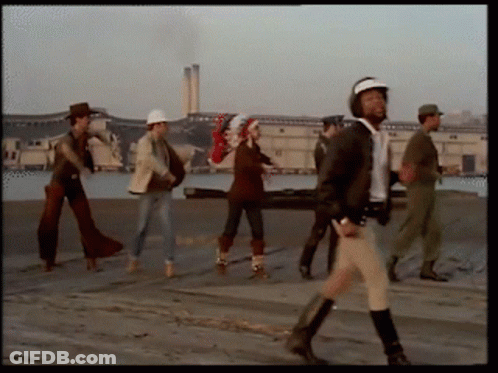 Group Walking Down Street With Man In Helmet GIF