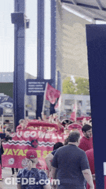 Group Walking Down Street With Ucgowell Sign GIF