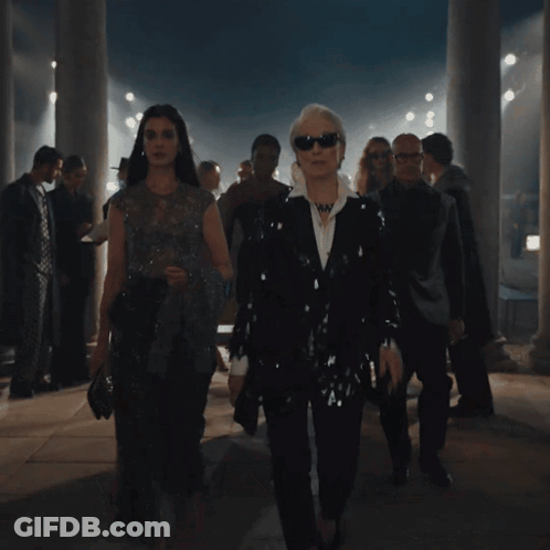 Group Walking In Dark Room With Columns GIF