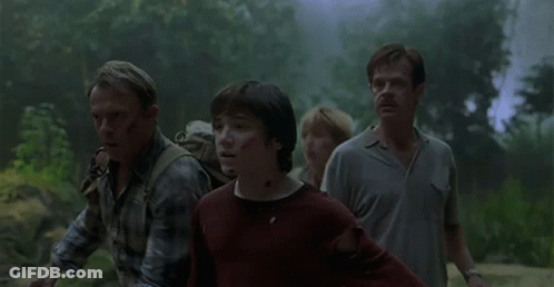 Group Walking In Forest With Dinosaur Emerging From Fog GIF