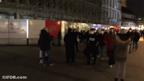 Group Wearing Face Masks Walking Past Kunstwerk Fence GIF