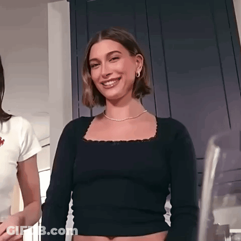 Hailey Baldwin Is Wearing A Black Crop Top And A Gold Necklace . GIF