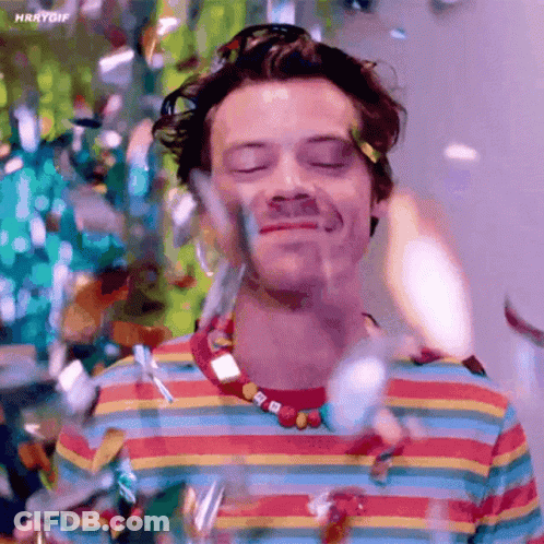 Harry Styles In Colorful Striped Shirt Holding Water GIF