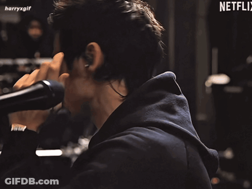 Harry Styles In Green Boa Holding Microphone GIF