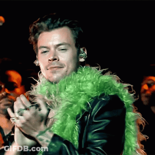 Harry Styles In Green Boa Holding Microphone GIF