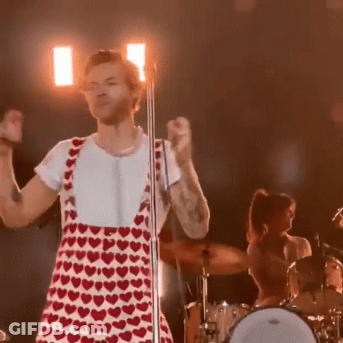 Harry Styles In Red And White Heart Dress At Microphone GIF