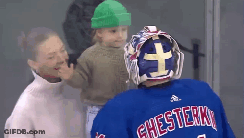 Hockey Goalie Holding Baby In Green Hat GIF