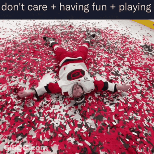 Hockey Player Laying On Ground Surrounded By Confetti Saying Don't Care Having Fun Playing GIF