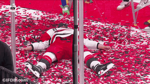 Hockey Player Laying On Red Carpet With Confetti GIF