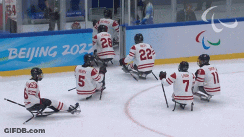 Hockey Players Sitting On Ice In Front Of Beijing 2022 Sign GIF