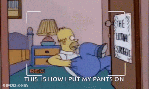 Homer Simpson Is Laying On A Bed With His Pants On And A Camera Recording Him . GIF