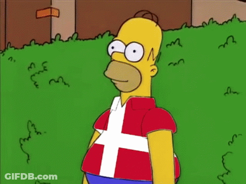 Homer Simpson Is Standing In The Grass Wearing A Shirt That Has A Flag On It GIF
