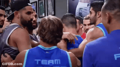 Huddled Men, One In Blue Team Jersey GIF