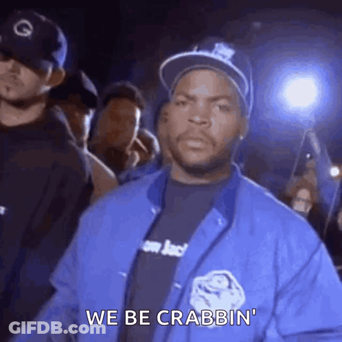 Ice Cube Is Wearing A Blue Jacket And A Hat While Standing In Front Of A Crowd Of People . GIF