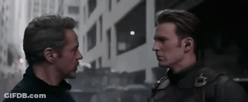 Iron Man And Captain America Are Standing Next To Each Other And Looking At Each Other In Front Of A Building . GIF