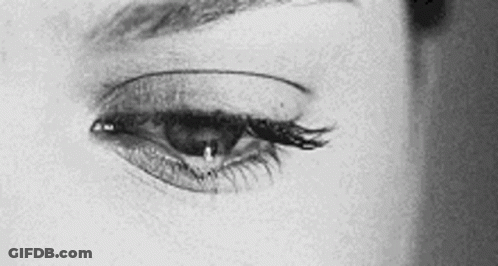 It Is A Black And White Photo Of A Woman 'S Eye With A Tear Coming Out Of It . GIF