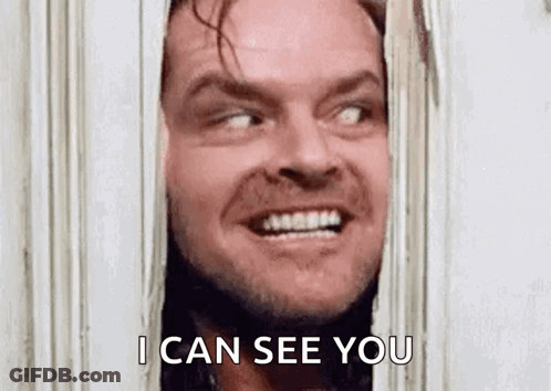 Jack Nicholson From The Shining Is Smiling While Looking Through A Door . GIF