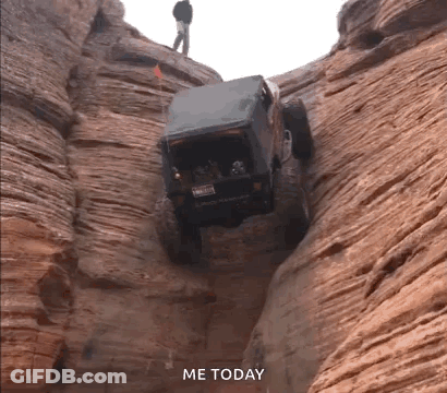 Jeep Driving Down Canyon With Man Standing On Top GIF