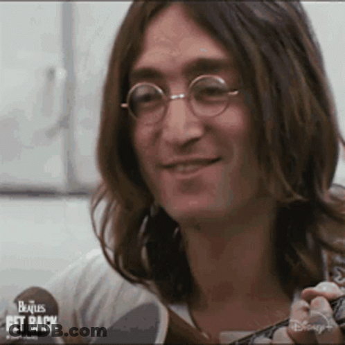 John Lennon Is Wearing Glasses And Holding A Guitar . GIF