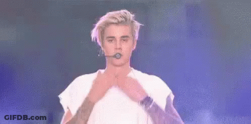 Justin Bieber Is Kissing His Lips While Holding A Microphone In His Hand . GIF