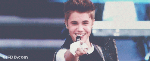 Justin Bieber Is Smiling And Pointing At The Camera While Holding A Microphone GIF