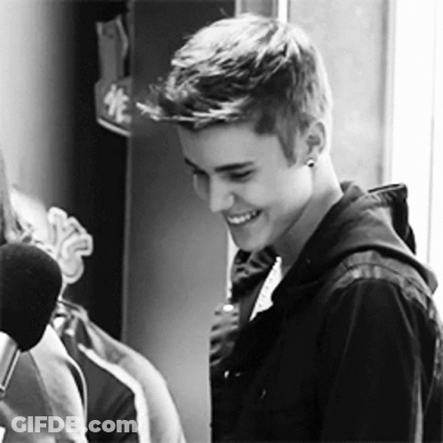 Justin Bieber Is Smiling In A Black And White Photo While Standing In Front Of A Microphone . GIF
