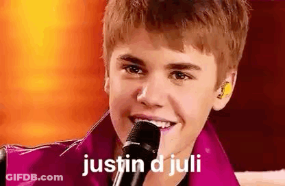 Justin Bieber Is Smiling While Holding A Microphone In His Hand . GIF