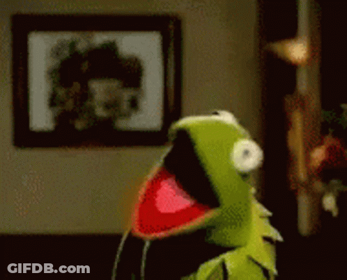 Kermit The Frog Is Standing In A Room With His Mouth Open And A Picture On The Wall Behind Him . GIF