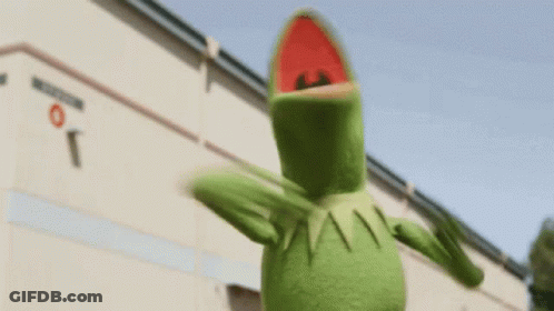 Kermit The Frog Is Standing In Front Of A Building . GIF