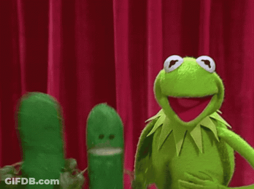 Kermit The Frog Is Standing Next To A Pickle On A Stage GIF