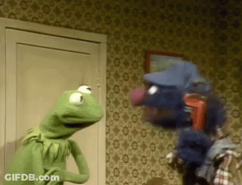 Kermit The Frog Is Standing Next To A Puppet In A Room . GIF
