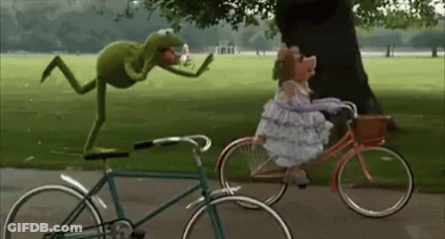 Kermit The Frog Is Standing On Top Of A Bicycle Next To A Muppet Riding A Bicycle . GIF